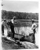 1930s three fishermen standing beside canoe holding fishing gear net backpack lake of the woods ontario by Anonymous