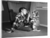 1950s boy in plaid shirt shaking finger at dog sitting up on rear legs by Anonymous