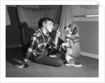 1950s boy in plaid shirt shaking finger at dog sitting up on rear legs by Anonymous