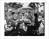 1930s three women and one man sitting at tropical pool side table talking together by Anonymous