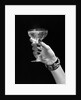1930s 1940s 1950s woman hand ornate metal bracelet holding up new year toast glass of champagne against black background by Anonymous