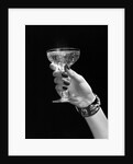 1930s 1940s 1950s woman hand ornate metal bracelet holding up new year toast glass of champagne against black background by Anonymous