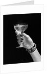 1930s 1940s 1950s woman hand ornate metal bracelet holding up new year toast glass of champagne against black background by Anonymous
