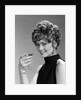 1960s glamorous woman with curly hair and dangling earrings smiling holding a champagne glass looking at camera by Anonymous