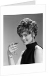 1960s glamorous woman with curly hair and dangling earrings smiling holding a champagne glass looking at camera by Anonymous