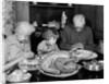1950s 1960s little girl look at turkey sitting between grandmother grandfather saying grace at table by Anonymous