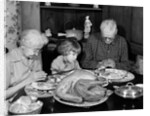 1950s 1960s little girl look at turkey sitting between grandmother grandfather saying grace at table by Anonymous
