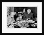 1950s 1960s little girl look at turkey sitting between grandmother grandfather saying grace at table by Anonymous