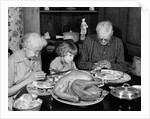 1950s 1960s little girl look at turkey sitting between grandmother grandfather saying grace at table by Anonymous
