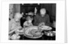 1950s 1960s little girl look at turkey sitting between grandmother grandfather saying grace at table by Anonymous