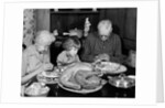 1950s 1960s little girl look at turkey sitting between grandmother grandfather saying grace at table by Anonymous