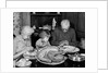 1950s 1960s little girl look at turkey sitting between grandmother grandfather saying grace at table by Anonymous