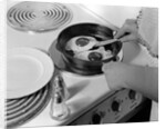 1940s 1950s woman hands frying eggs in iron skillet on electric stove salt and pepper shakers by Anonymous