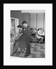 1950s teen couple playing juke box in malt shop with other teens in booths by Anonymous