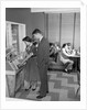 1950s teen couple playing juke box in malt shop with other teens in booths by Anonymous