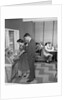 1950s teen couple playing juke box in malt shop with other teens in booths by Anonymous
