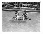 1930s 1940s couple drinking while floating in a pool on a rubber raft at florida resort by Anonymous