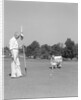 1930s 1940s elderly men on golf green one holding flag the other kneels lining up his putt by Anonymous