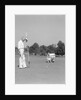 1930s 1940s elderly men on golf green one holding flag the other kneels lining up his putt by Anonymous