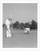 1930s 1940s elderly men on golf green one holding flag the other kneels lining up his putt by Anonymous