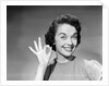 1950s woman smiling wearing pearl necklace looking at camera making okay gesture with hand by Anonymous