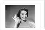 1950s woman smiling wearing pearl necklace looking at camera making okay gesture with hand by Anonymous