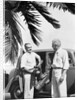 1930s 2 elderly men standing by car carrying golf bag palm tree frond in corner by Anonymous