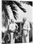 1930s 2 elderly men standing by car carrying golf bag palm tree frond in corner by Anonymous