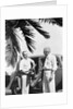 1930s 2 elderly men standing by car carrying golf bag palm tree frond in corner by Anonymous