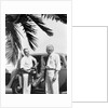 1930s 2 elderly men standing by car carrying golf bag palm tree frond in corner by Anonymous