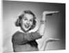 1950s 1960s happy smiling blond woman gesturing with hands showing size of something looking at camera by Anonymous