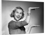 1950s 1960s happy smiling blond woman gesturing with hands showing size of something looking at camera by Corbis