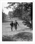 1930s couple man woman each carrying a golf bag walking down the fairway of the golf course by Anonymous