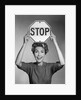 1950s 1960s smiling woman holding stop sign above her head looking at camera by Anonymous