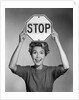 1950s 1960s smiling woman holding stop sign above her head looking at camera by Anonymous