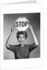 1950s 1960s smiling woman holding stop sign above her head looking at camera by Anonymous