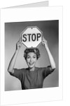 1950s 1960s smiling woman holding stop sign above her head looking at camera by Anonymous