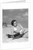 1930s woman leaning in wooden chair on beach wearing printed dress holding magazine looking thoughtful by Anonymous