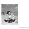 1930s woman leaning in wooden chair on beach wearing printed dress holding magazine looking thoughtful by Anonymous
