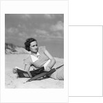 1930s woman leaning in wooden chair on beach wearing printed dress holding magazine looking thoughtful by Anonymous