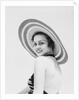 1930s woman wearing striped halter top and very wide brim straw hat looking at camera over shoulder by Anonymous