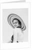 1930s woman wearing striped halter top and very wide brim straw hat looking at camera over shoulder by Anonymous