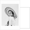 1930s woman wearing striped halter top and very wide brim straw hat looking at camera over shoulder by Anonymous