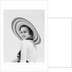 1930s woman wearing striped halter top and very wide brim straw hat looking at camera over shoulder by Anonymous