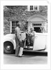 1940s senior retired couple loading golf clubs into white convertible car in front stone house by Anonymous