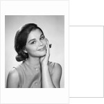 1960s smiling brunette young woman hand to cheek facial expression gesture looking at camera by Anonymous