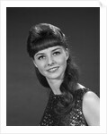 1960s portrait of smiling young woman in sequin dress looking at camera by Anonymous