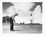 1960s older couple on golfing green man putting by Anonymous