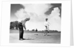 1960s older couple on golfing green man putting by Anonymous