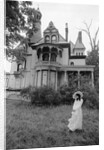 1970s woman in victorian costume standing on front lawn of large abandoned haunted victorian home by Anonymous